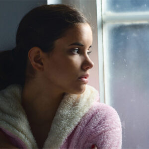 Girsl looking sadly out of the window